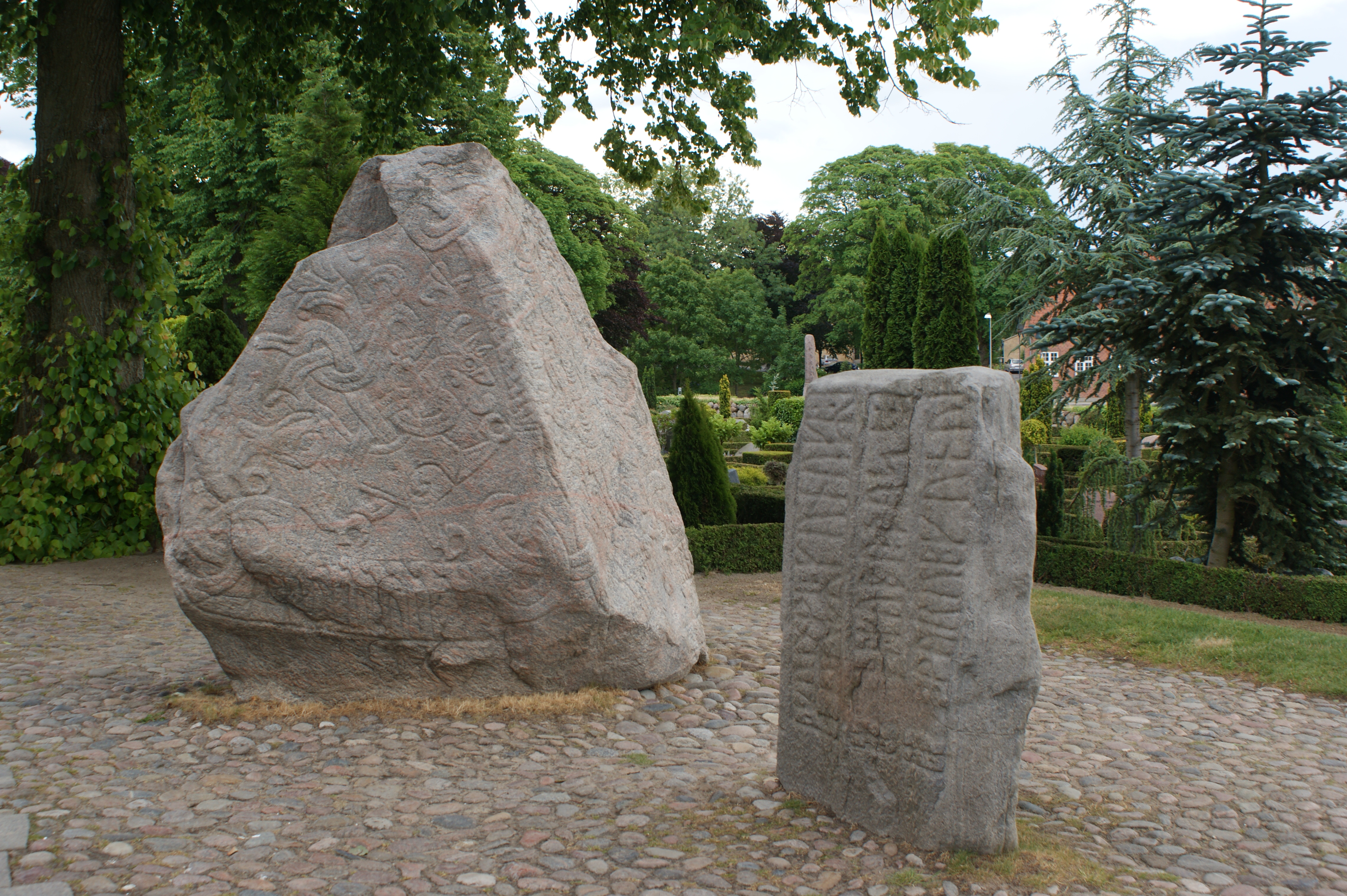 Die historischen Jelling-Steine bei Kongernes Jelling mit Bilddarstellung und Runen – Foto bei Wikimedia Commons