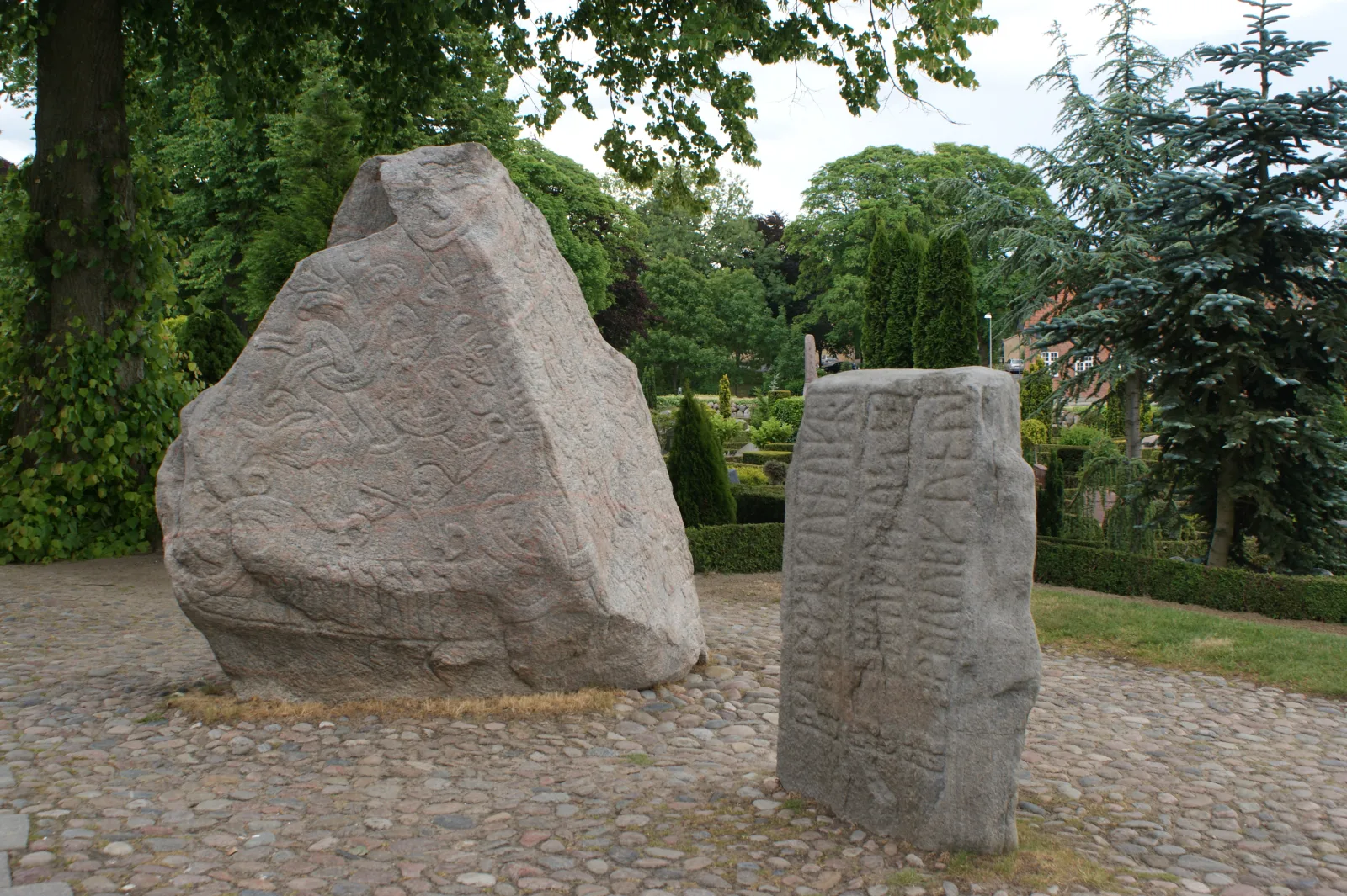 Die historischen Jelling-Steine bei Kongernes Jelling mit Bilddarstellung und Runen – Foto bei Wikimedia Commons